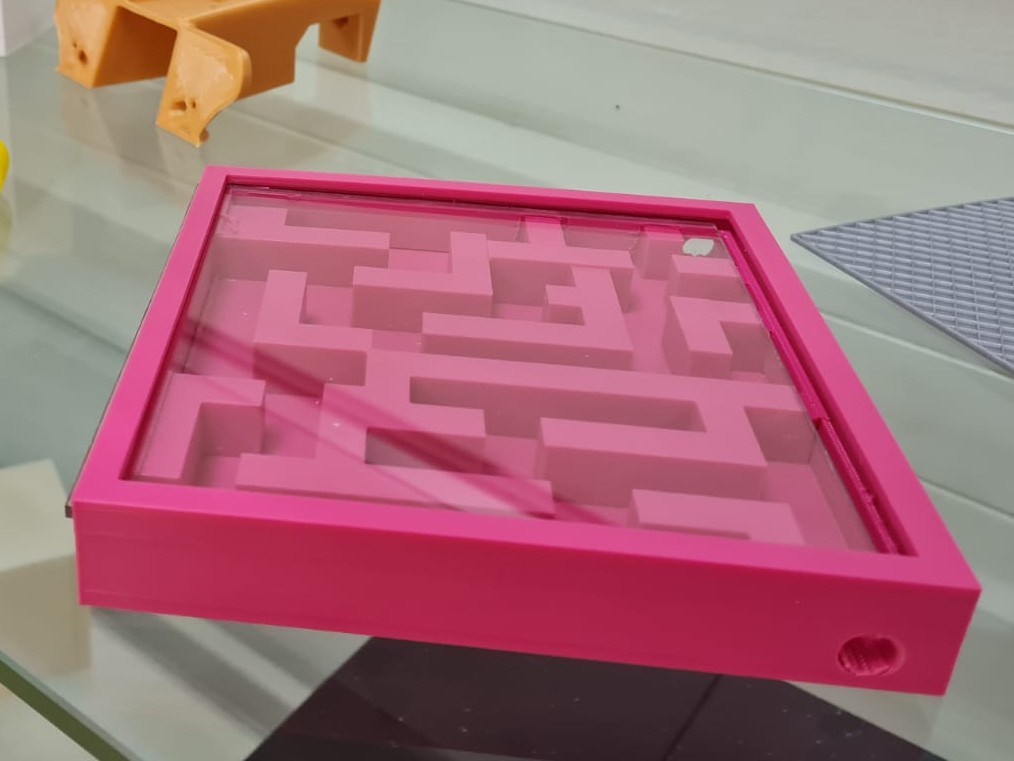 3D gedrucktes pinkes Kugellabyrinth mit durchsichtiger Plastikscheibe davor.