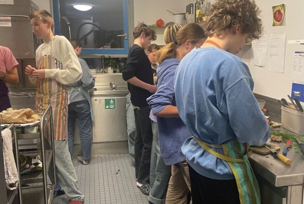 Jugendliche stehen in einer Küche und kochen.