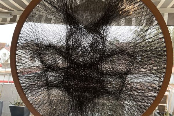 Bildern einer Biene durch das Spannen von Fäden in einem Holzreifen